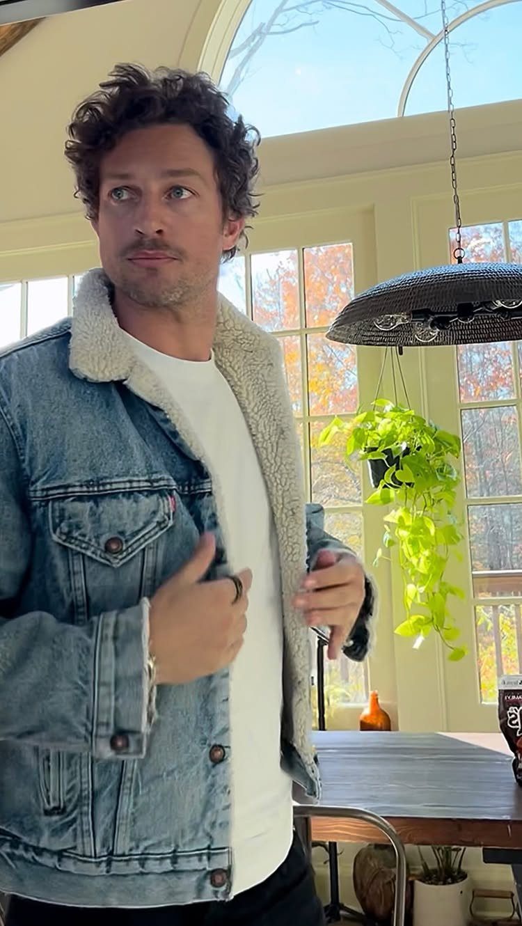 Man wearing a light blue oversized denim jacket with a white sherpa collar over a white t-shirt.