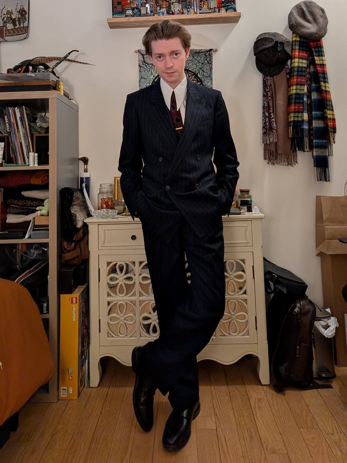 A young man wearing a dark pinstriped double-breasted power suit and tie.
