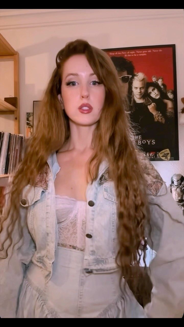 Woman with long wavy hair wearing a light-wash denim jacket and matching denim skirt.