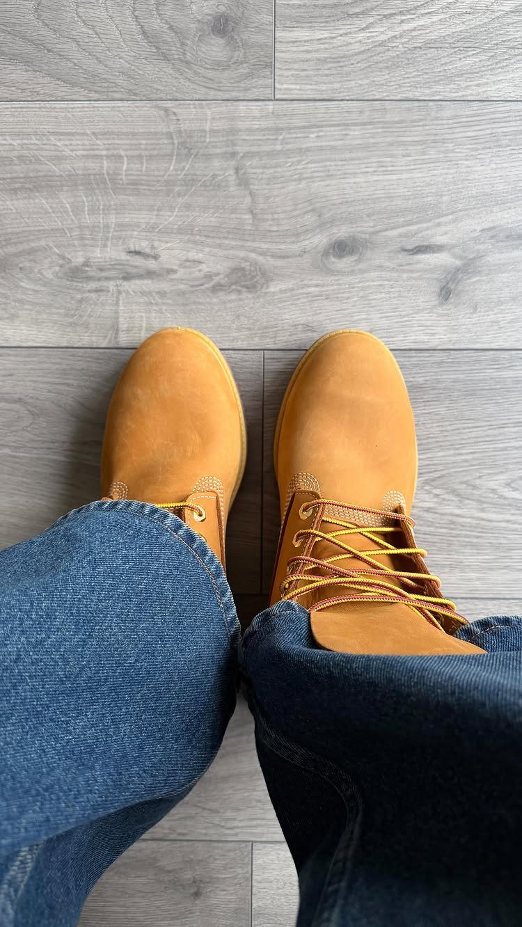 Tan suede boots and blue denim jeans on a grey wooden floor.