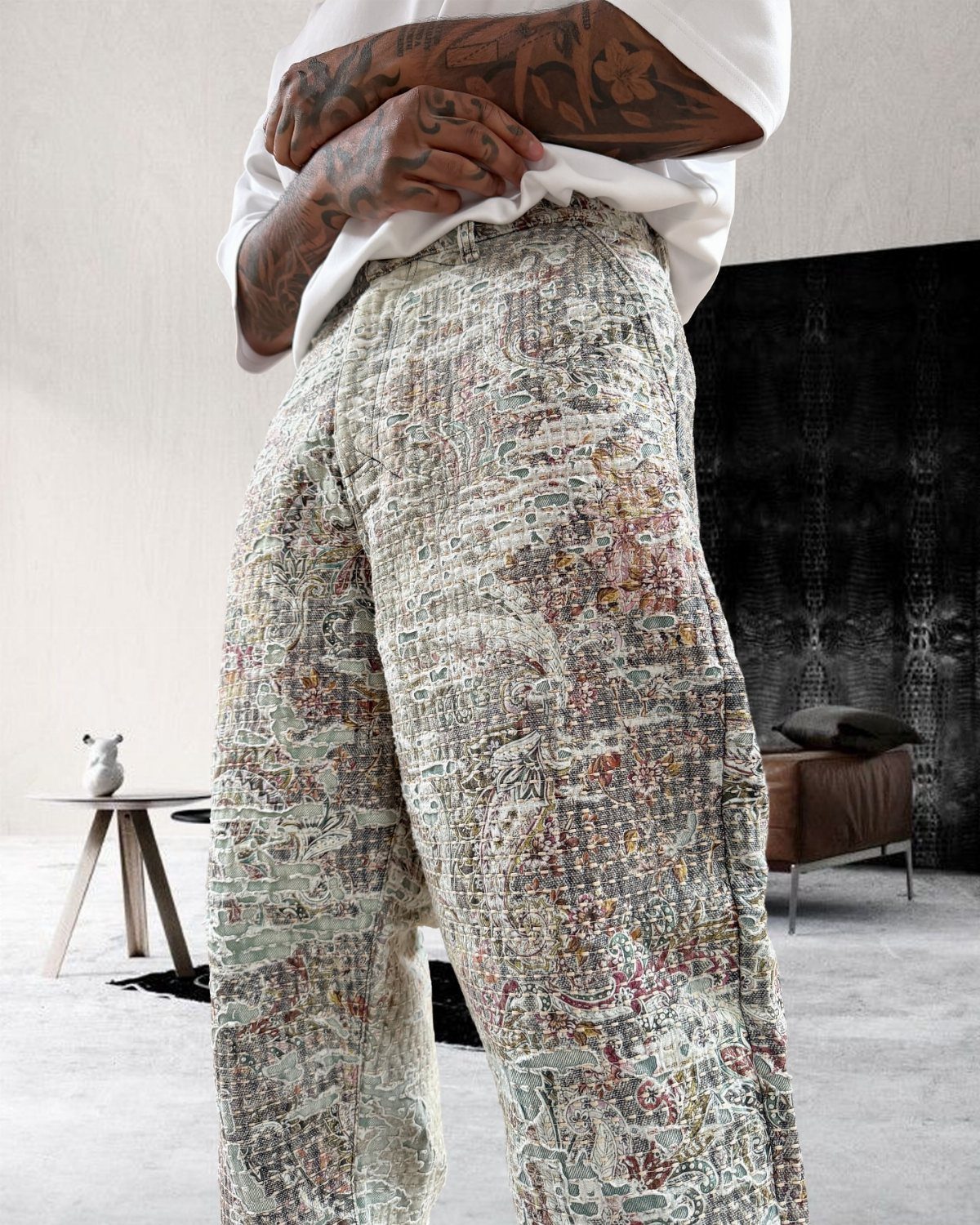 Person wearing patterned tapestry trousers with intricate colorful designs and a white shirt.