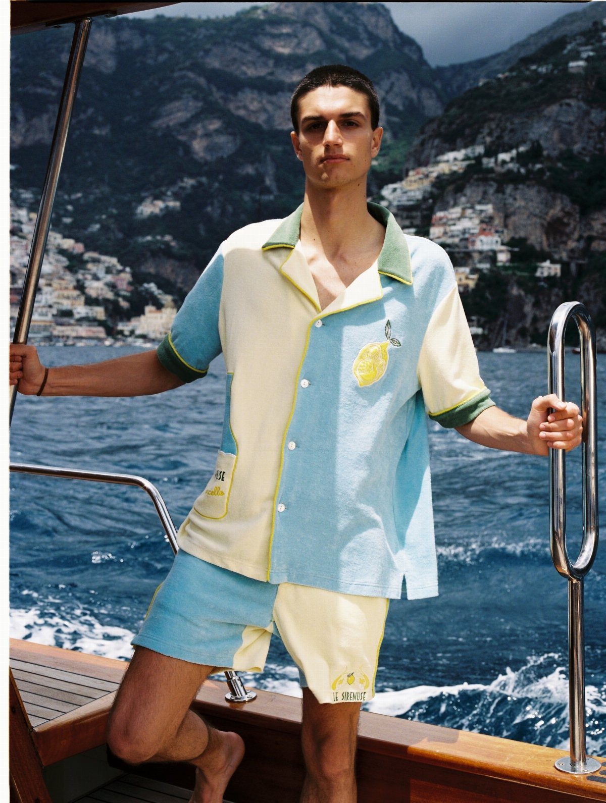 Man wearing a light blue and yellow short-sleeved cabana shirt and matching shorts on a boat.