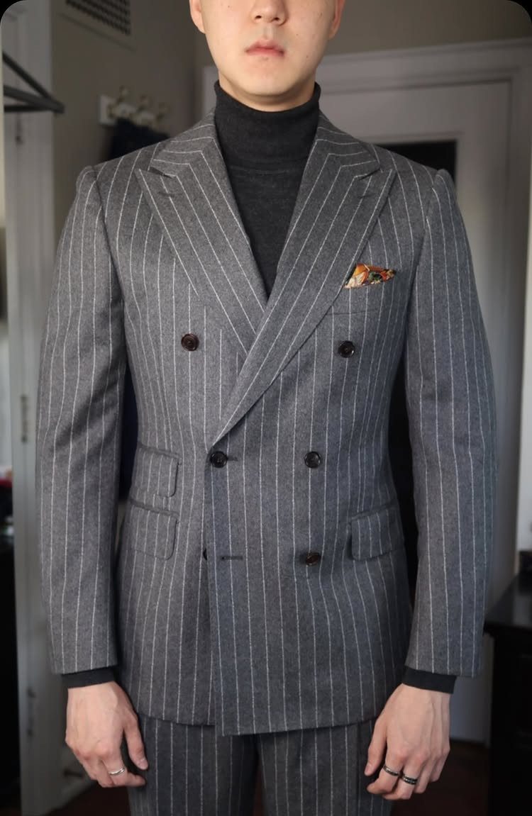 Man wearing a charcoal gray double-breasted pinstripe suit and black turtleneck.