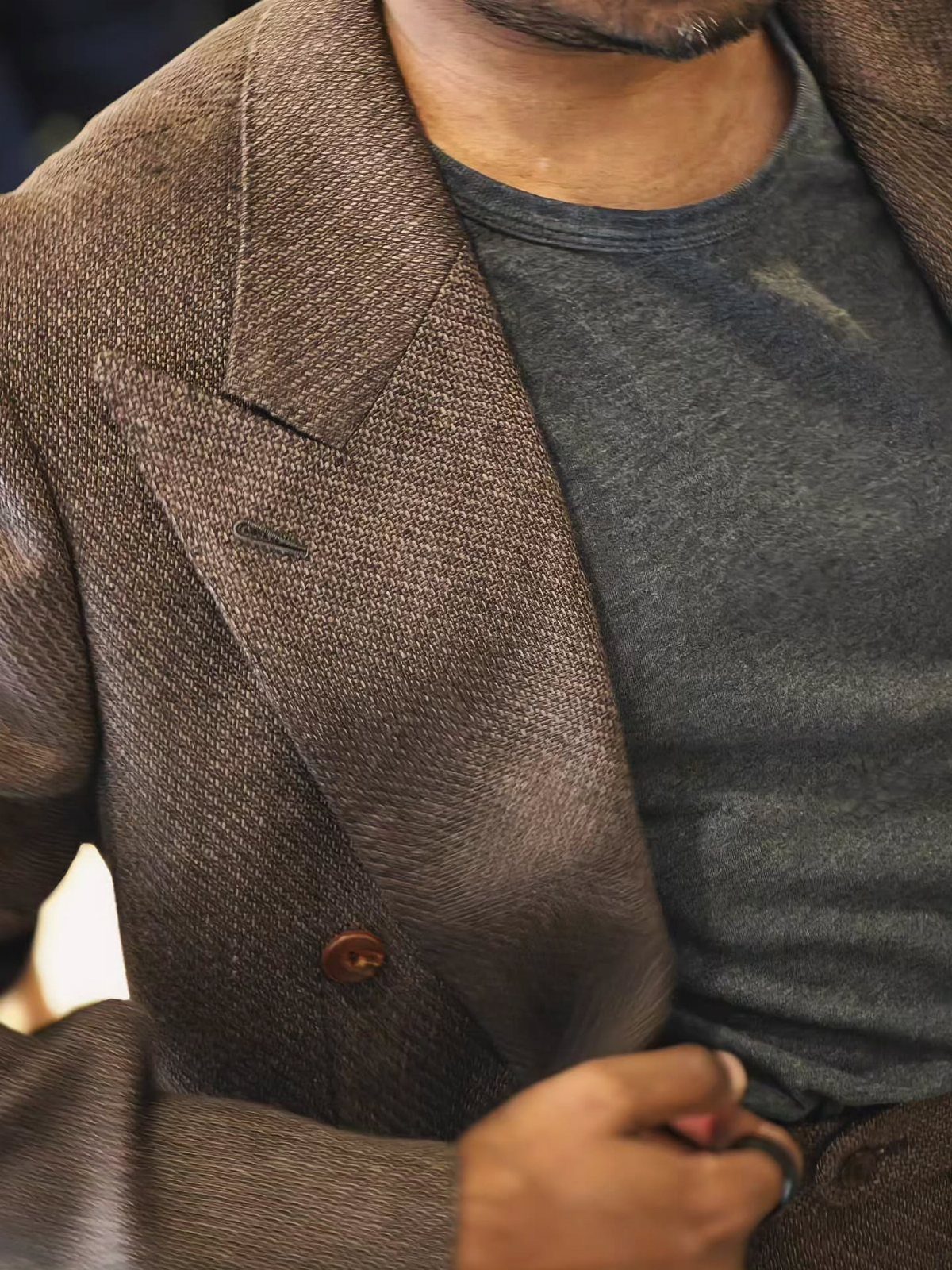 A man wearing a textured brown unstructured blazer over a gray t-shirt.