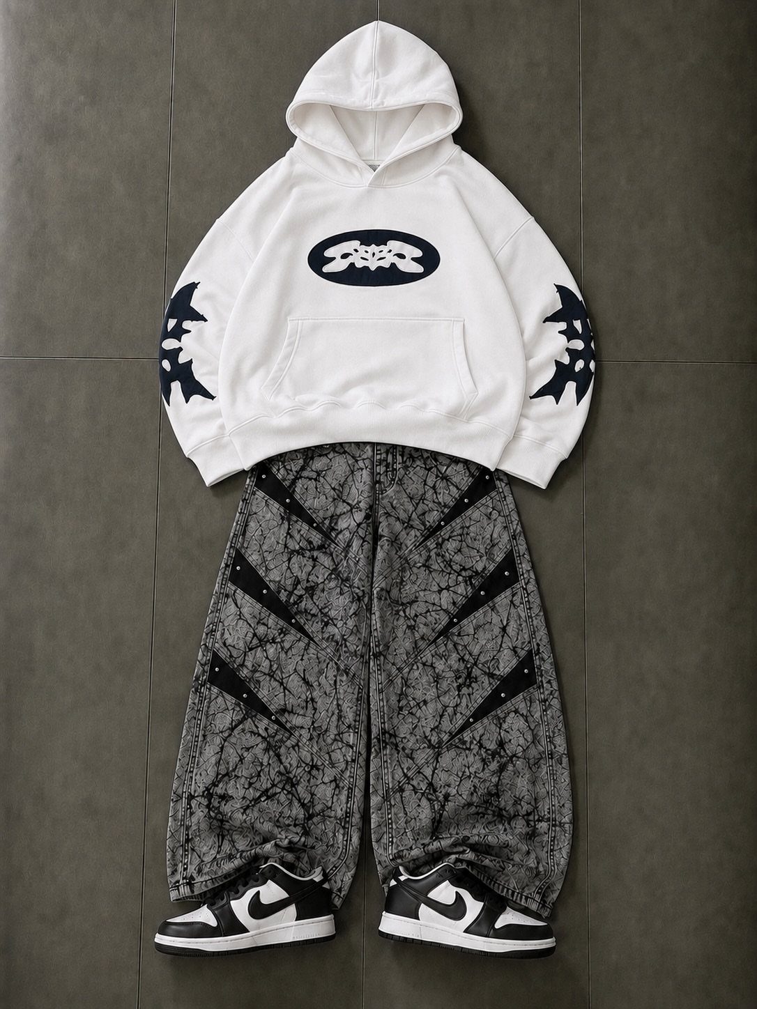 White graphic hoodie with black patterns, patterned wide-leg pants, and black and white sneakers.