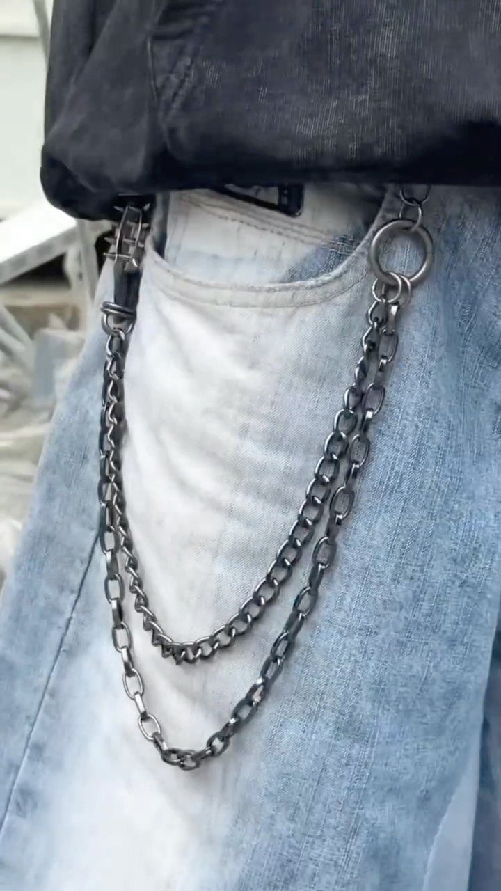 Dark metal chains hanging from the belt loops of light blue denim jeans.