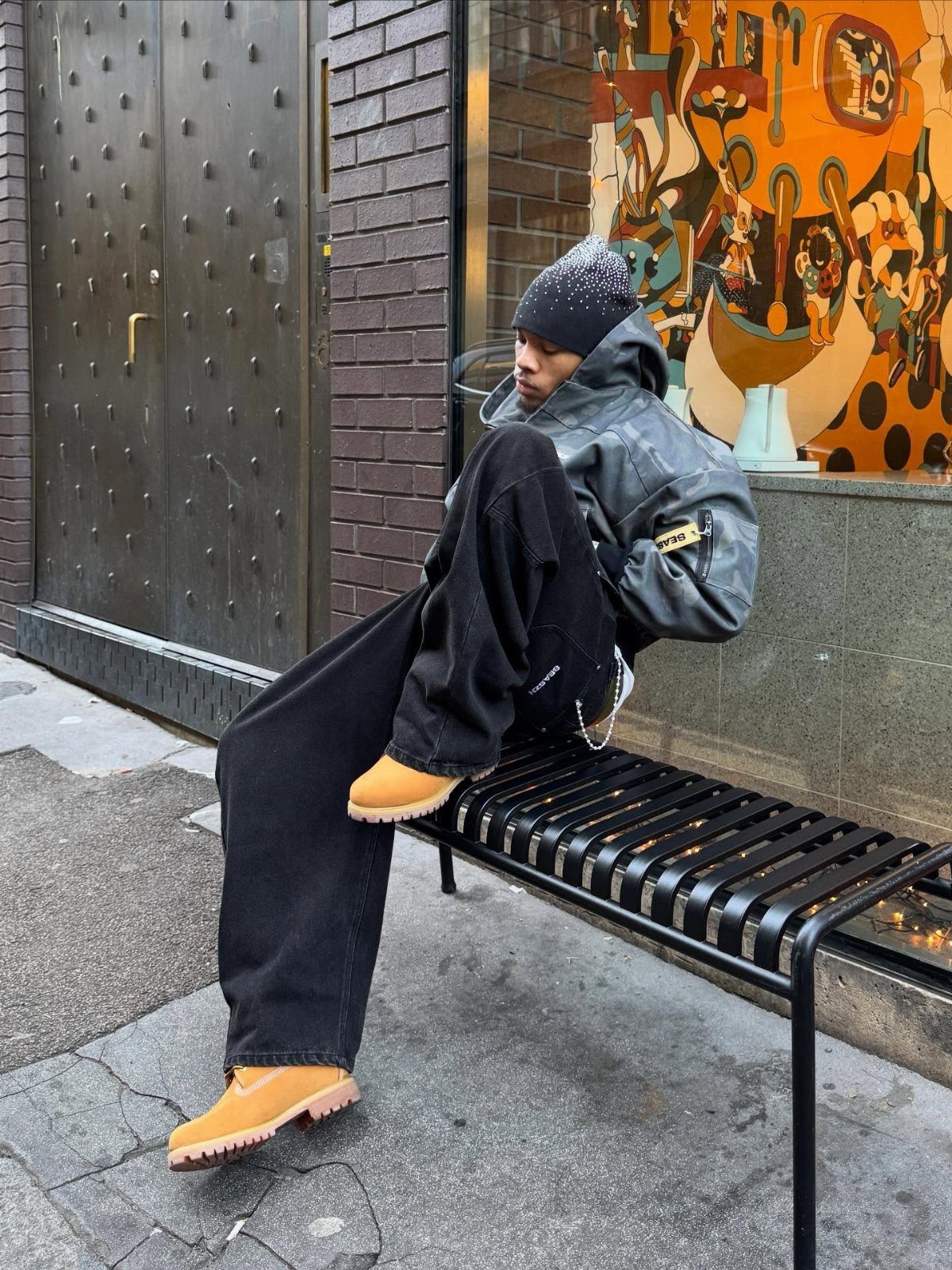 Man sitting on a bench wearing black trousers and tan suede work boots.