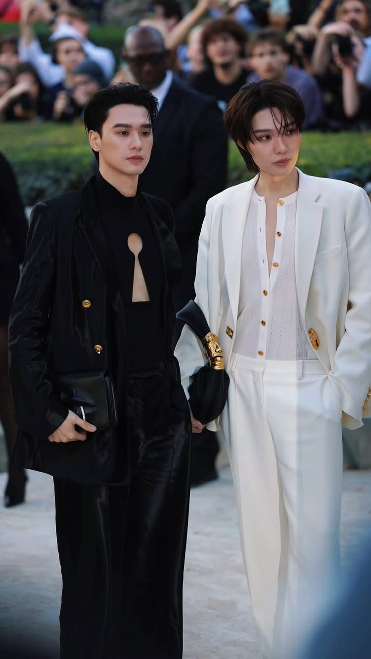 Two people walking together wearing contrasting all-black and all-white high-fashion outfits.