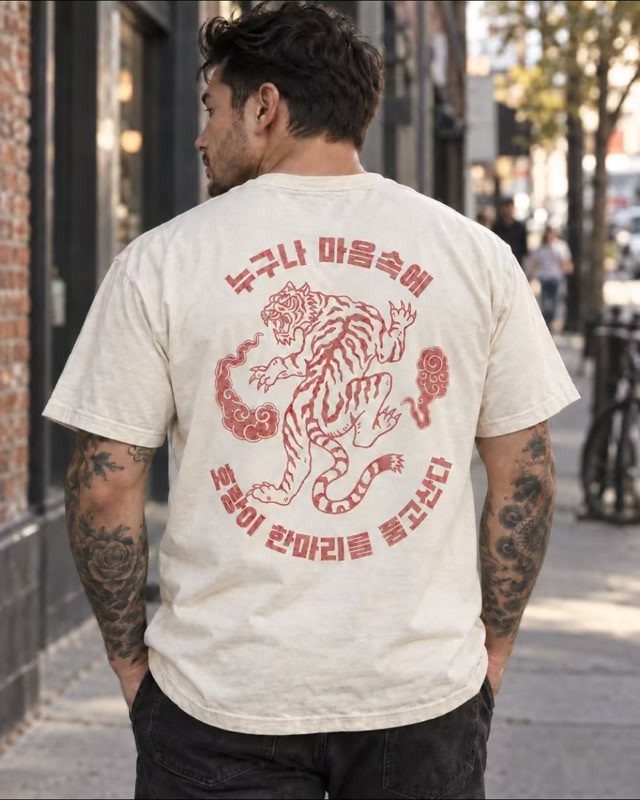 Man wearing a cream t-shirt with a red tiger graphic and Korean text on the back.