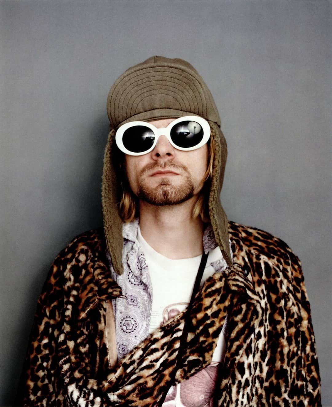 Man wearing large white bug-eye sunglasses, a tan trapper hat, and a leopard print coat.