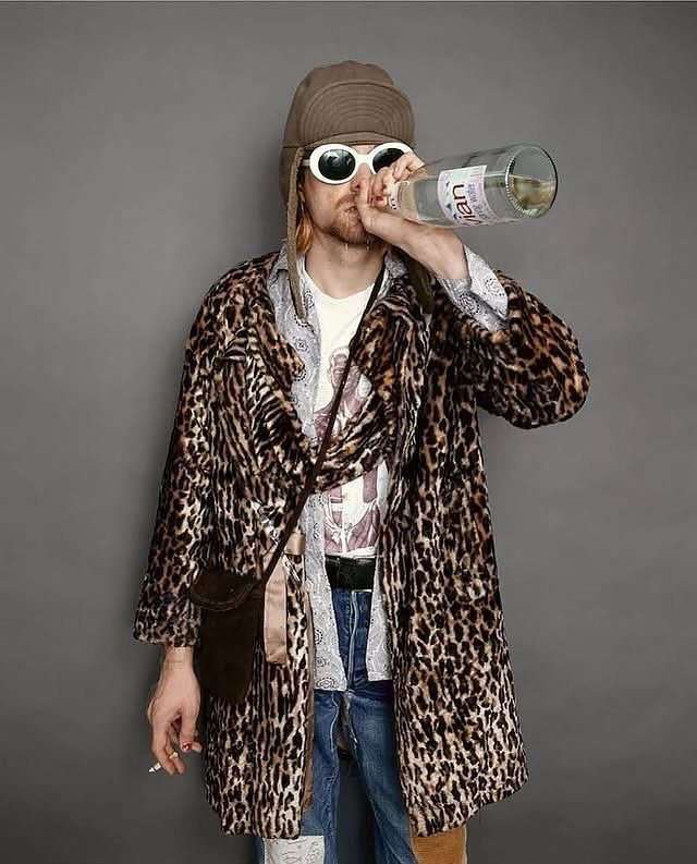 Man wearing layered clothing including a leopard print coat, patterned shirt, and graphic t-shirt.