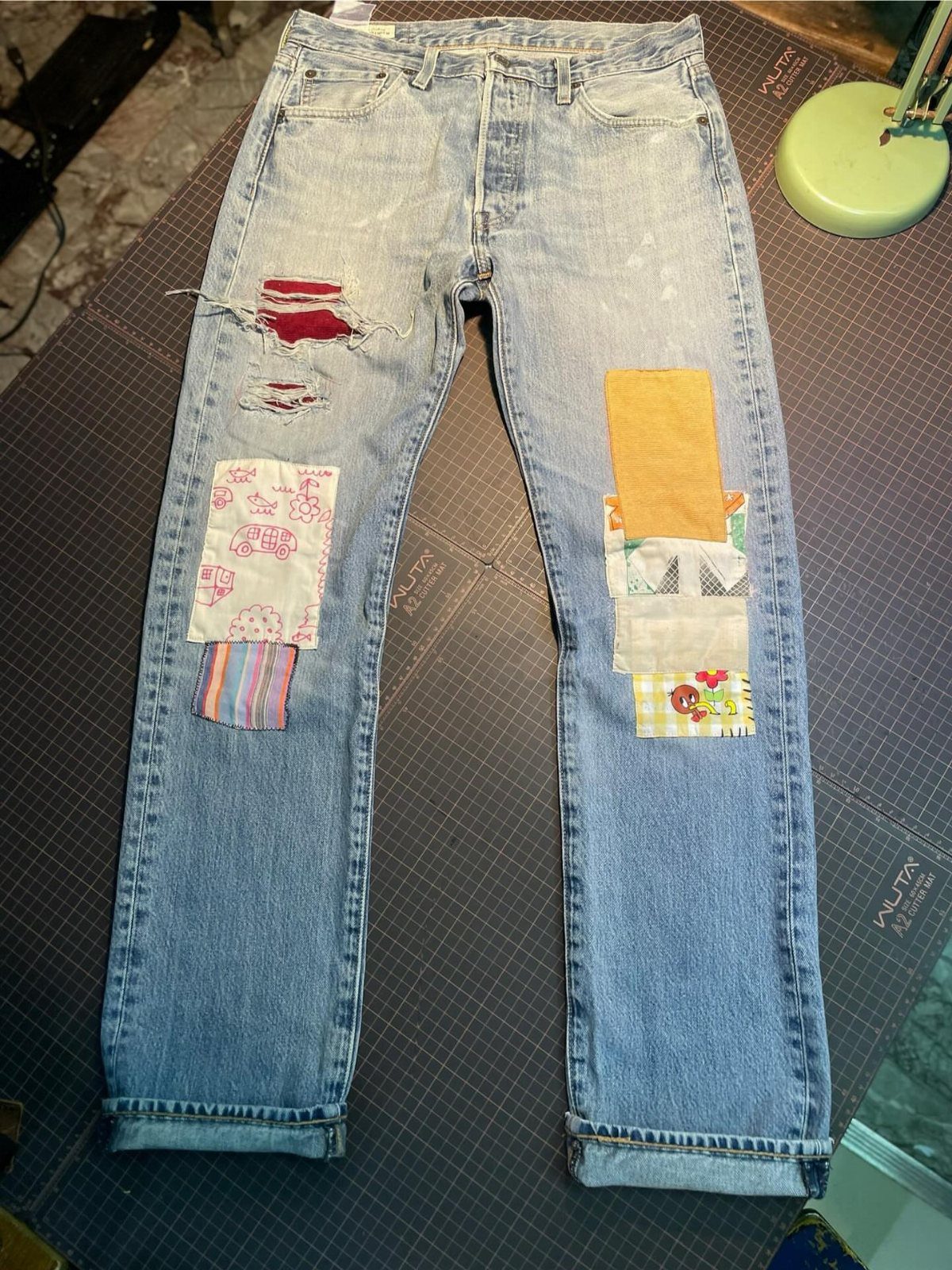 Light blue distressed denim jeans with various colorful fabric patches sewn onto the legs.