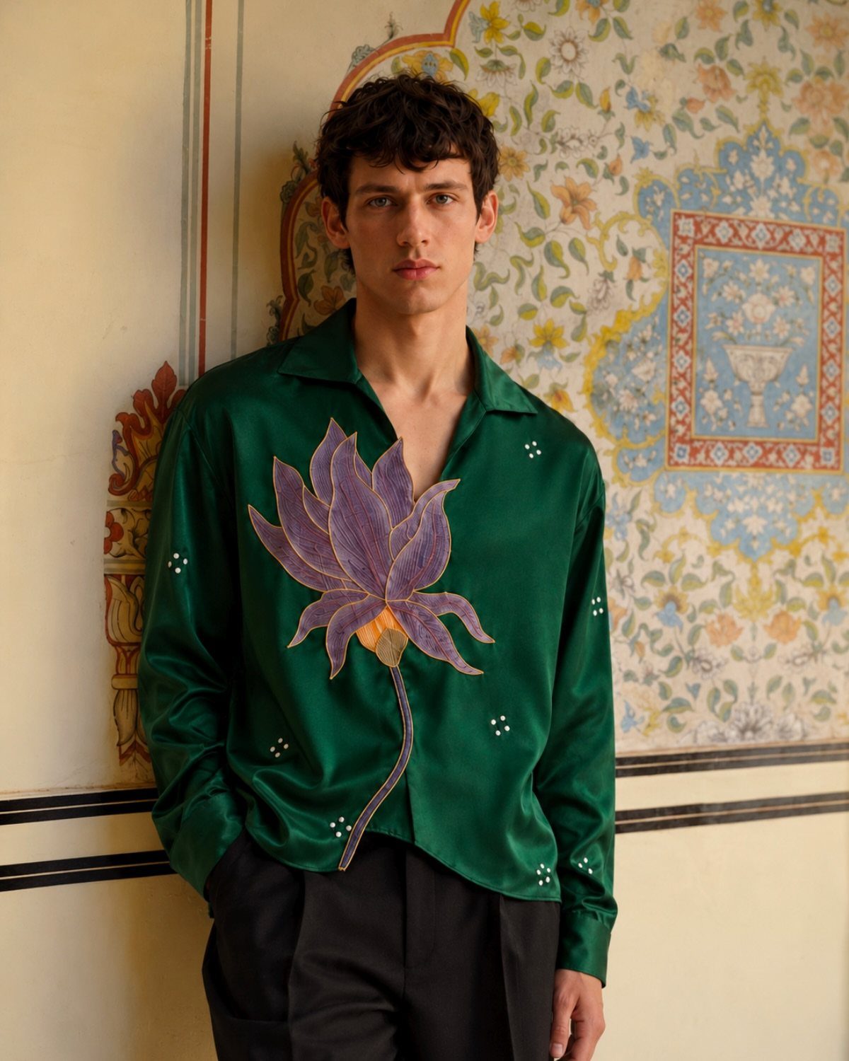 Man wearing a bold emerald green satin shirt with a large purple lotus embroidery.
