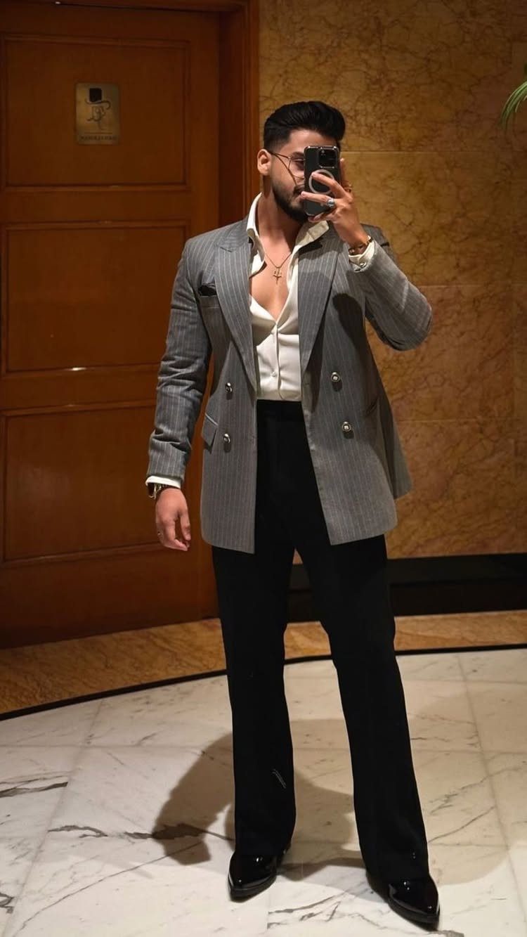 Man posing in a grey double-breasted blazer, white shirt, and black trousers.