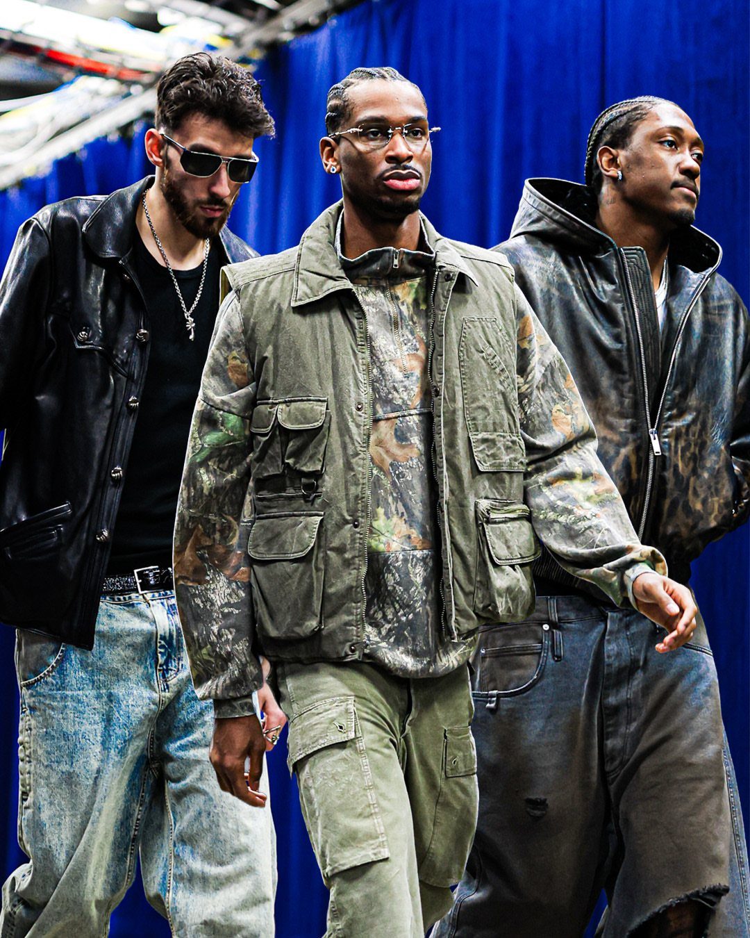 Three men walking while wearing various streetwear styles including leather jackets and utility vests.