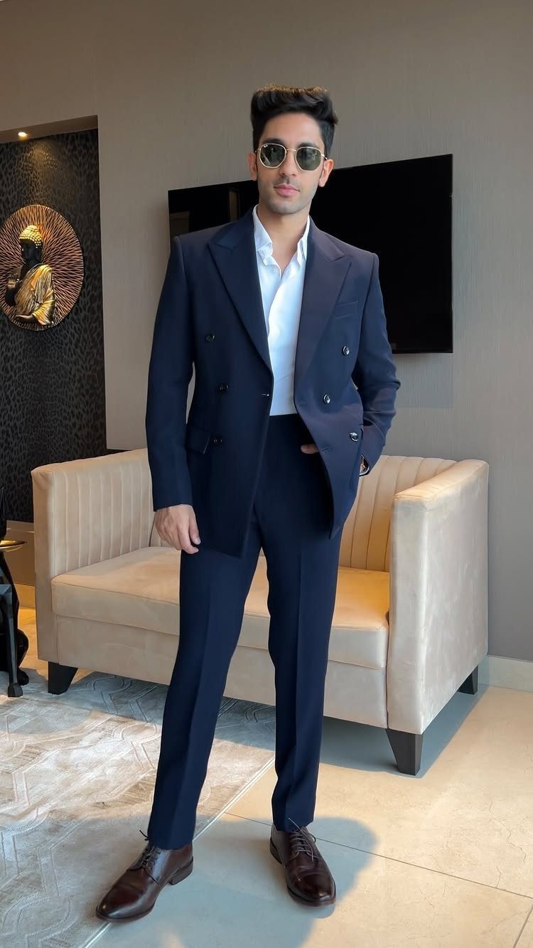 Man posing in a navy double-breasted blazer, white shirt, and matching navy trousers.