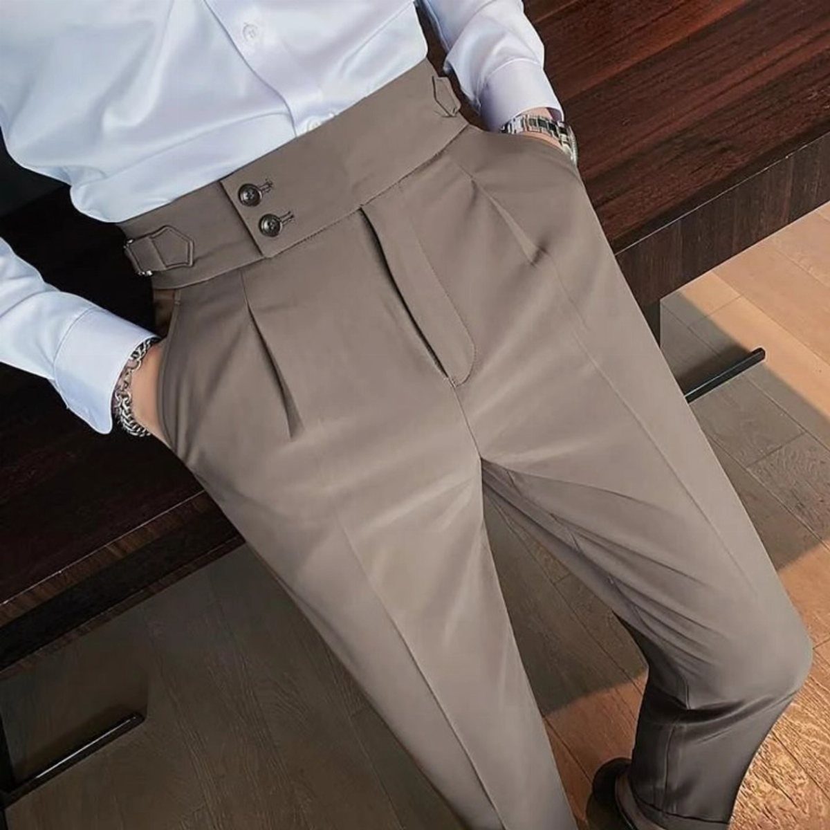Person wearing high-waisted taupe trousers and a white button-down shirt.