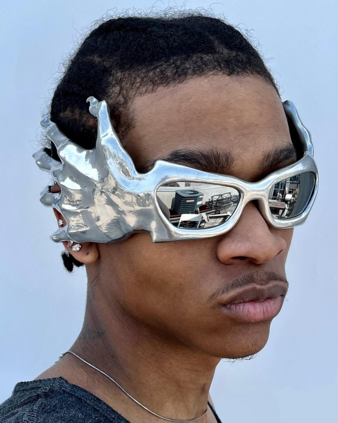 A person wearing large, silver metallic sunglasses shaped like hands framing their face.