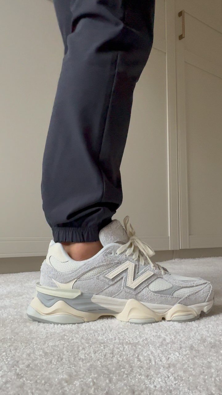 Grey and white chunky New Balance sneakers worn with dark navy blue jogger pants.