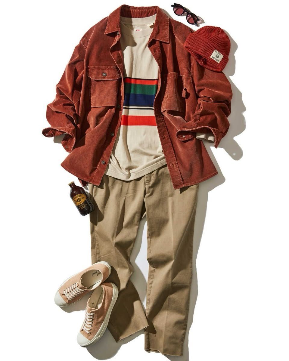 Flat lay of a rust corduroy shirt, striped t-shirt, tan pants, and pink sneakers.