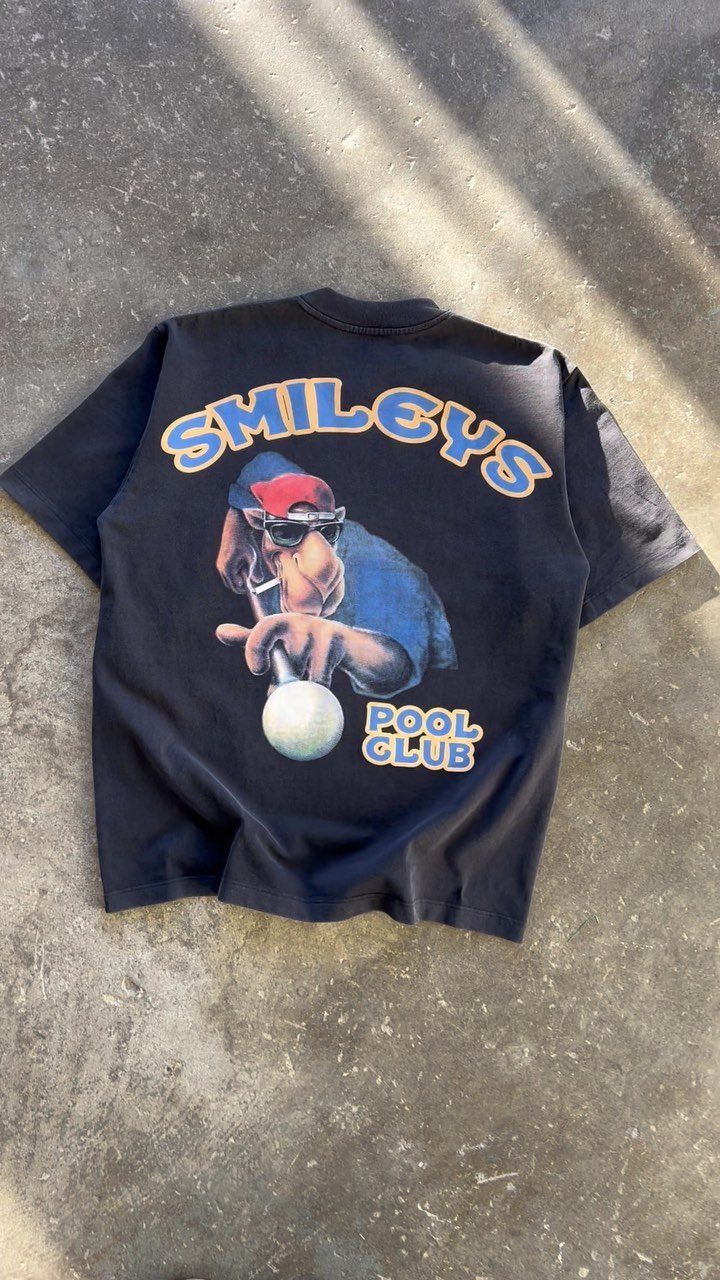 Black t-shirt with a large colorful graphic of a character and the text Smileys Pool Club.