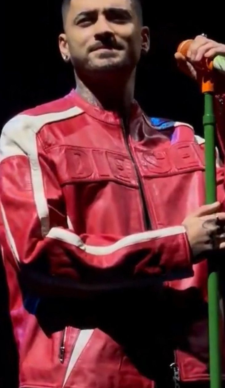 Man in a red Diesel leather racing jacket holding a green microphone stand.